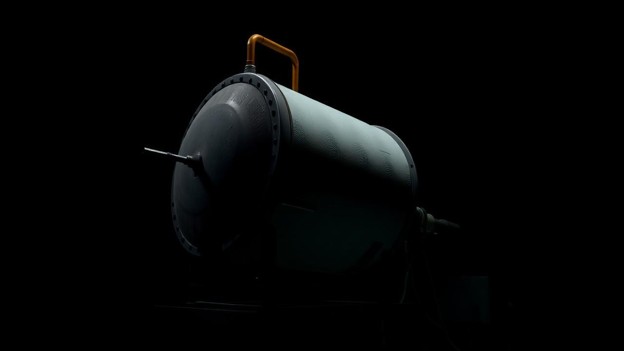 Cylindrical shell-and-tube thermal storage vessel on a dark laboratory rig
